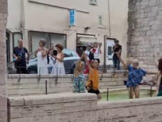 Turisti entrano nella fontana di Santa Chiara e fanno attività motoria in acqua, come in piscina